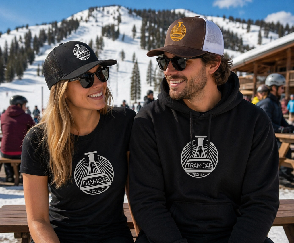 Two people sitting on a bench in a snowy mountain setting, wearing branded clothing.